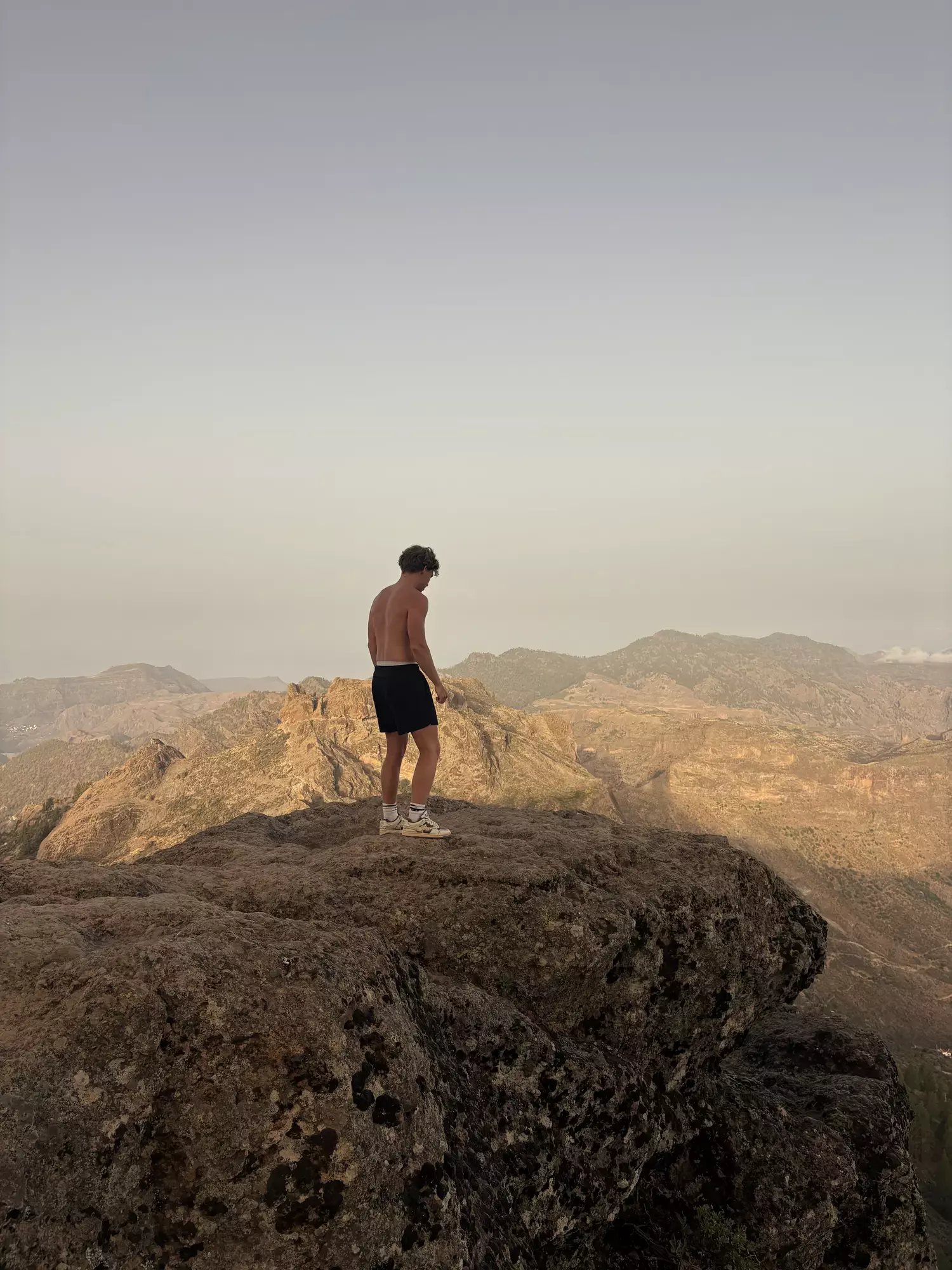 Wandelaar op een rotsblok met uitzicht over het bergachtige binnenland tijdens de Roque Nublo hike