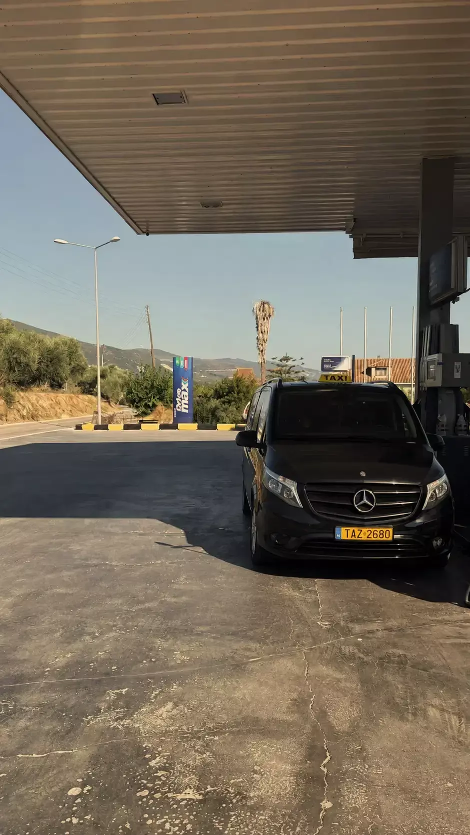 Zwarte Mercedes-taxibus geparkeerd onder de overkapping van een tankstation op zakynthos
