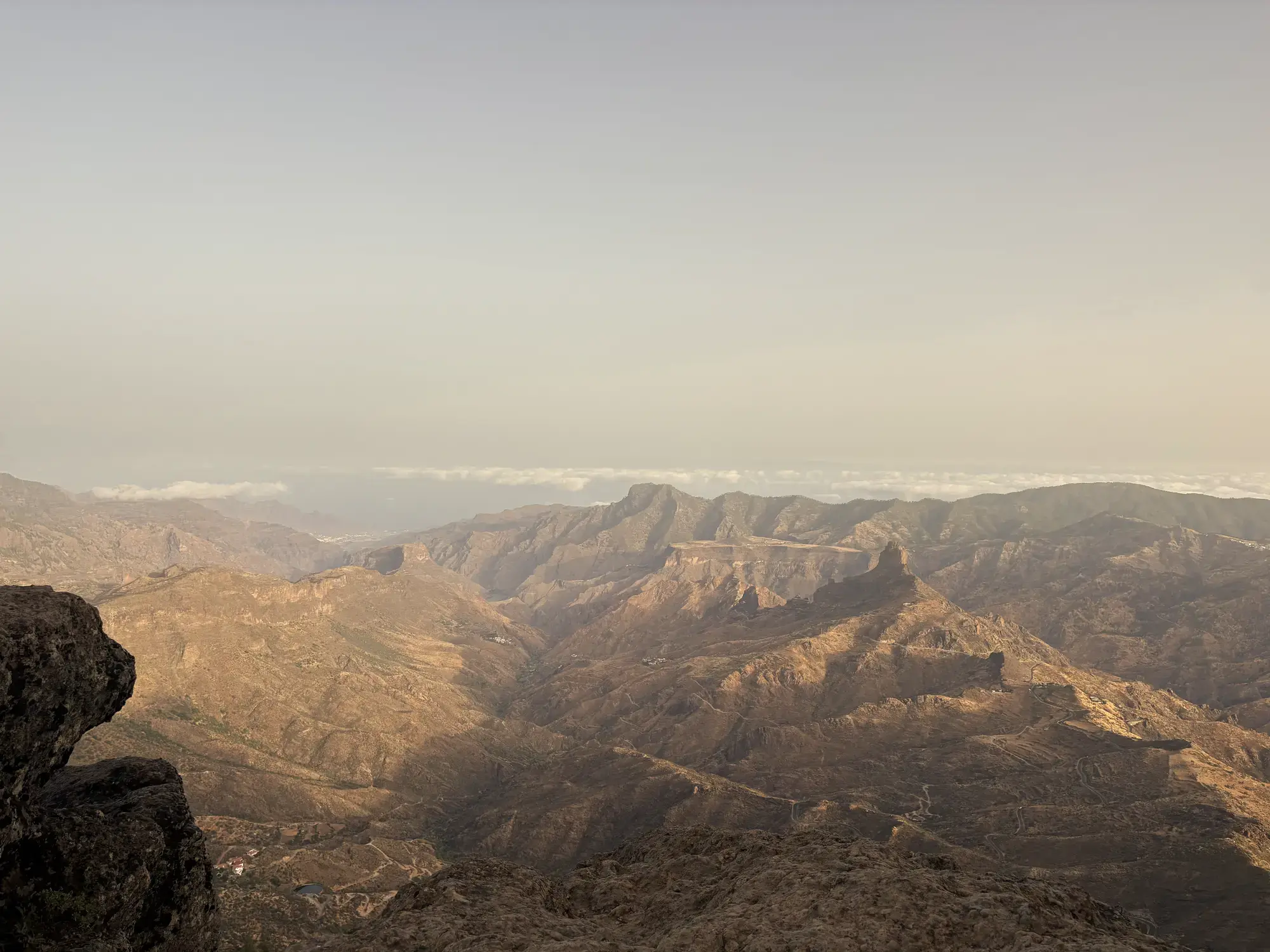 Ruig berglandschap met diepe dalen en een wolkenzee aan de horizon in warm avondlicht Roque Nublo