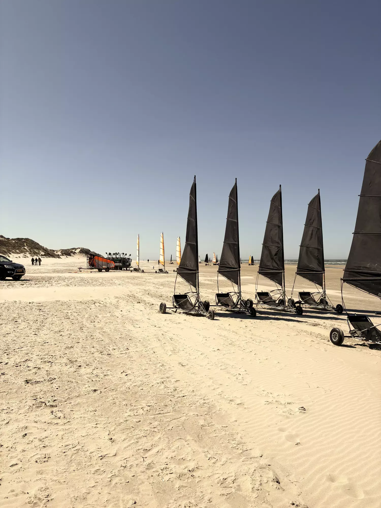 Rij geparkeerde blokarts met zwarte zeilen op het witte zandstrand van Terschelling, klaar voor het blokarten