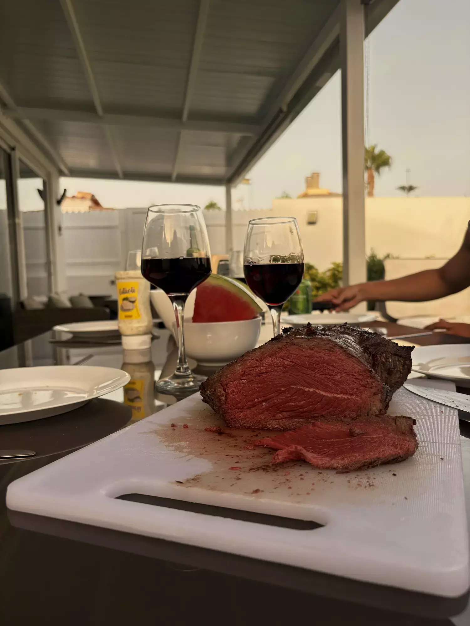 Gesneden rosbief op een snijplank met glazen rode wijn op het overdekte terras van Villa Palmera in Maspalomas