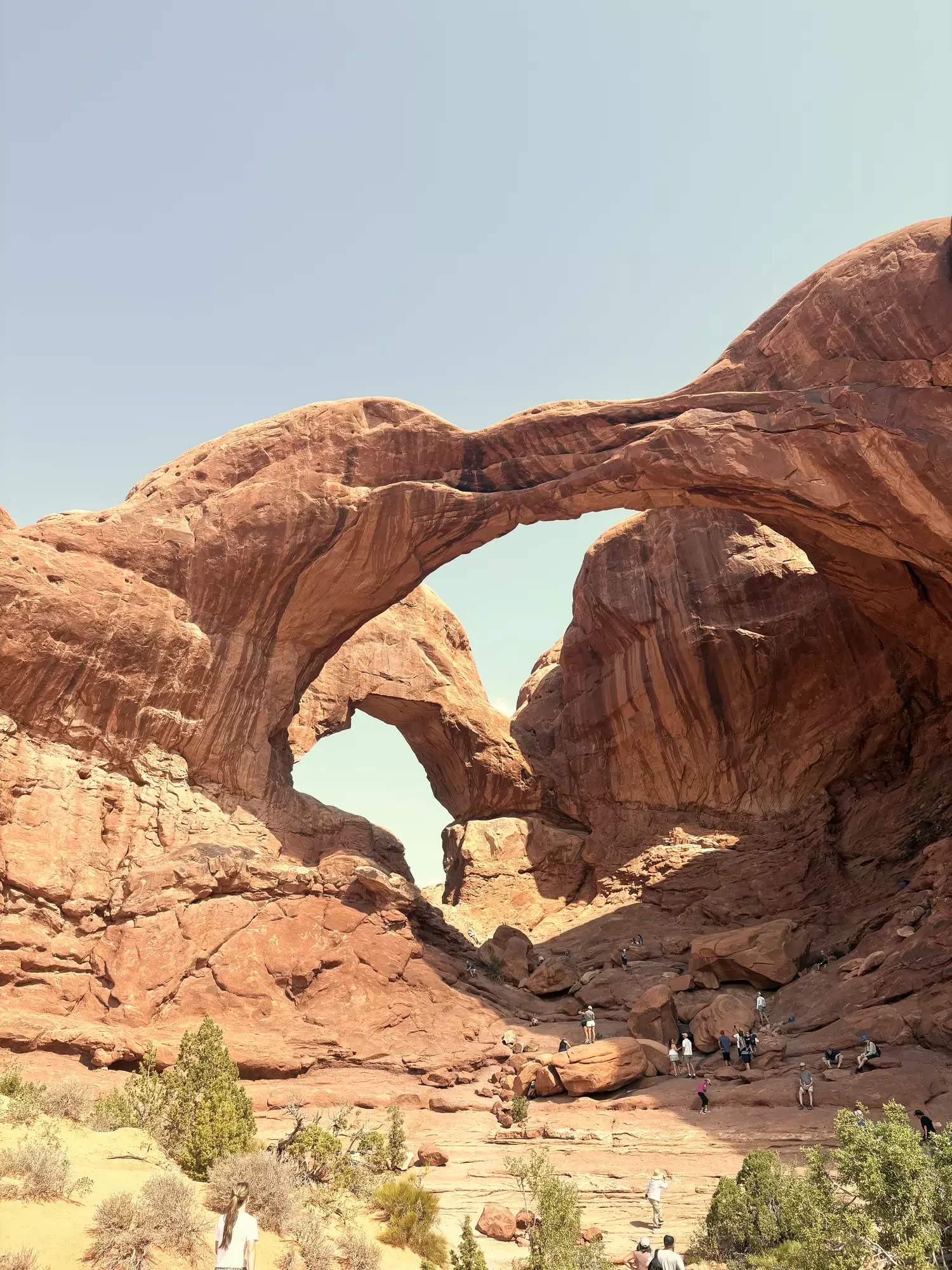 De Double Arch van rode zandsteen met wandelaars onderaan in Arches National Park in Utah
