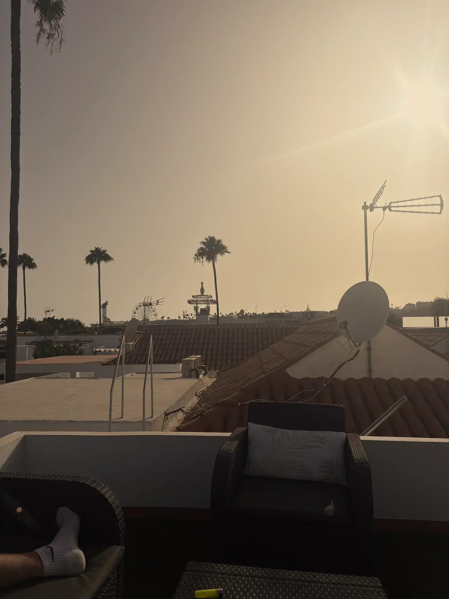 Uitzicht vanaf het dakterras van Villa Palmera over daken en palmbomen in Maspalomas, met het reuzenrad van Holiday World in de verte