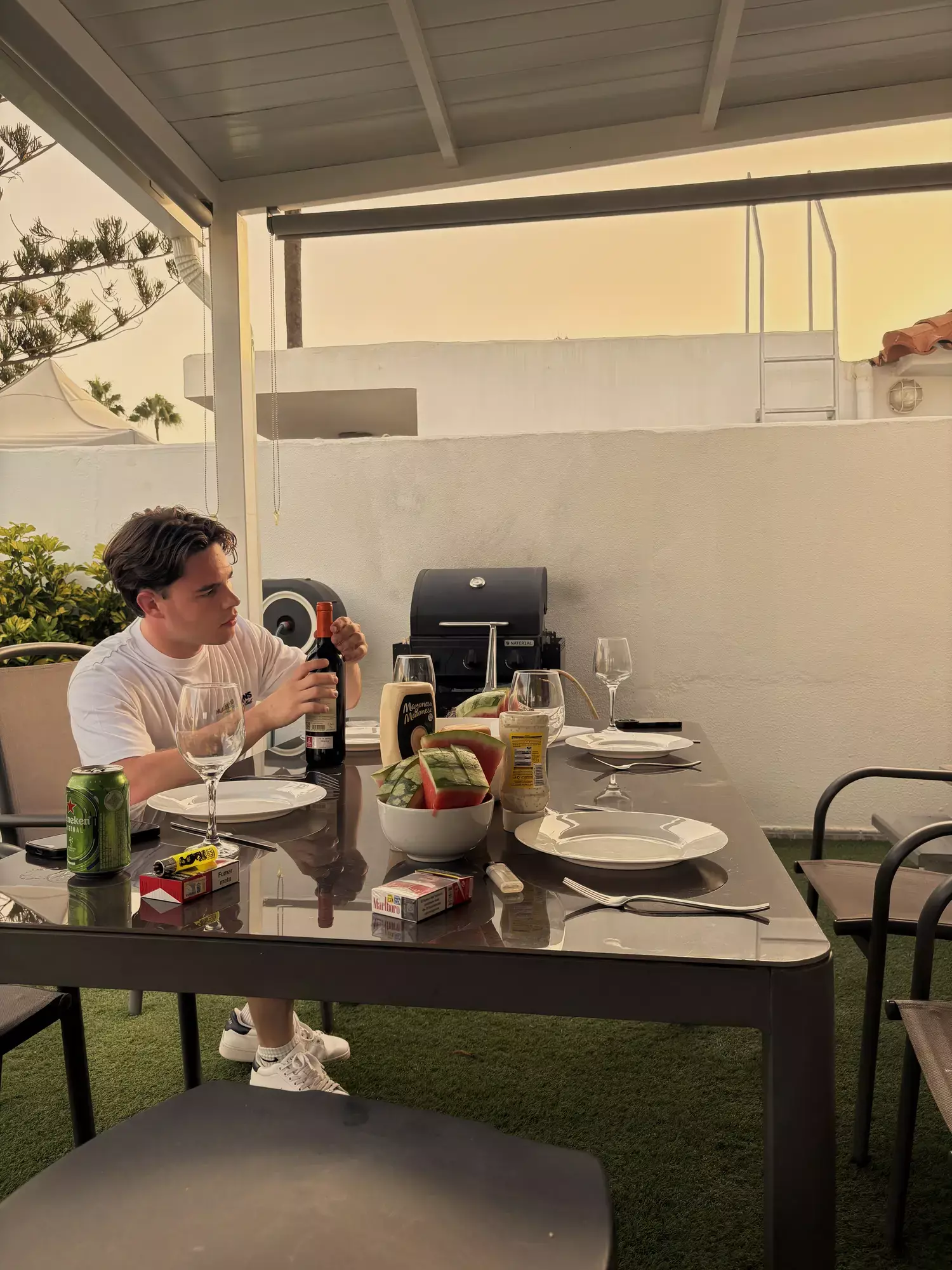 Jongeman aan een gedekte tafel op het overdekte terras van een vakantievilla in Maspalomas tijdens een barbecue