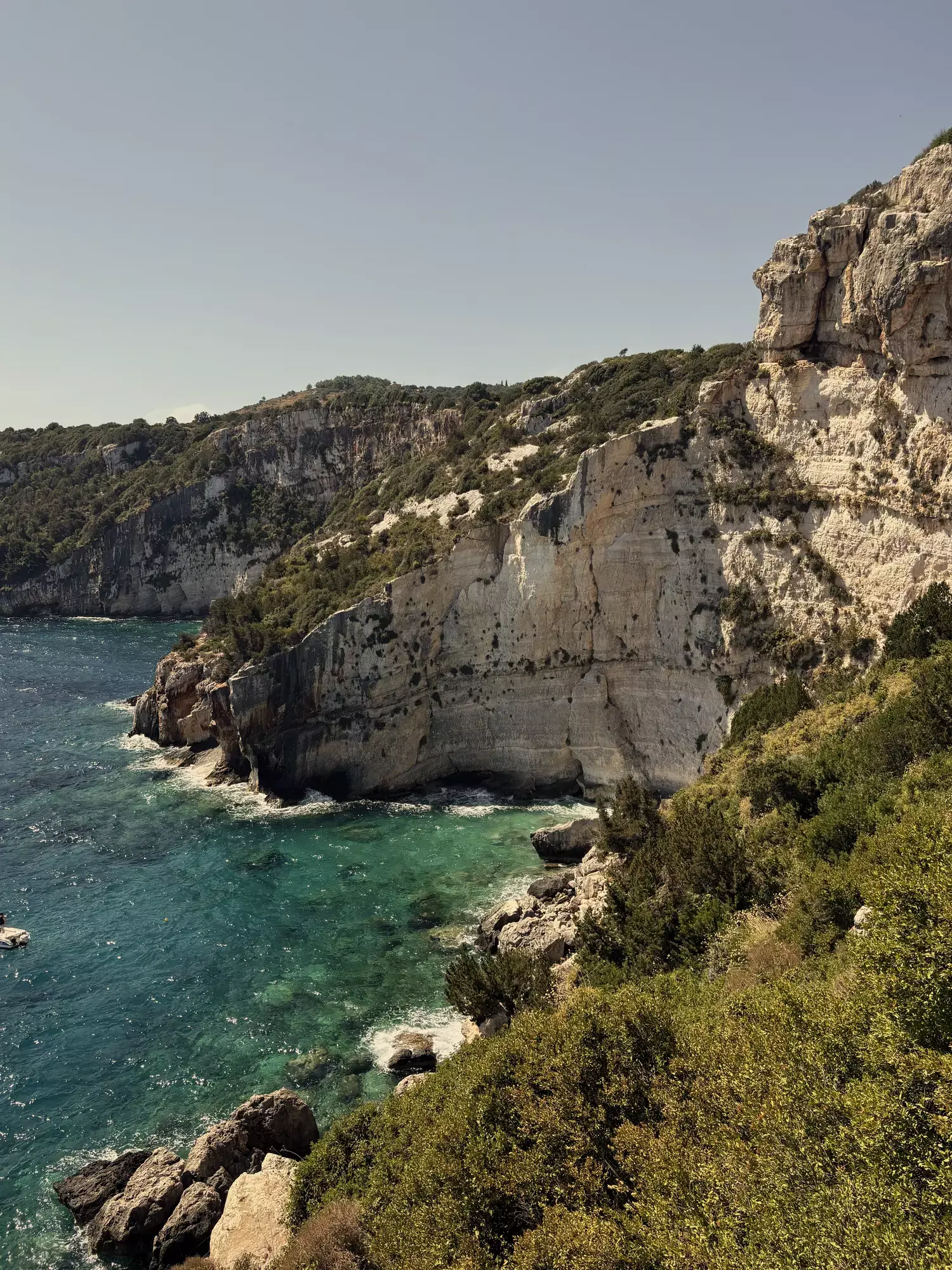 Witte kalksteenkliffen en groene begroeiing boven turquoise zee aan de kust van Zakynthos