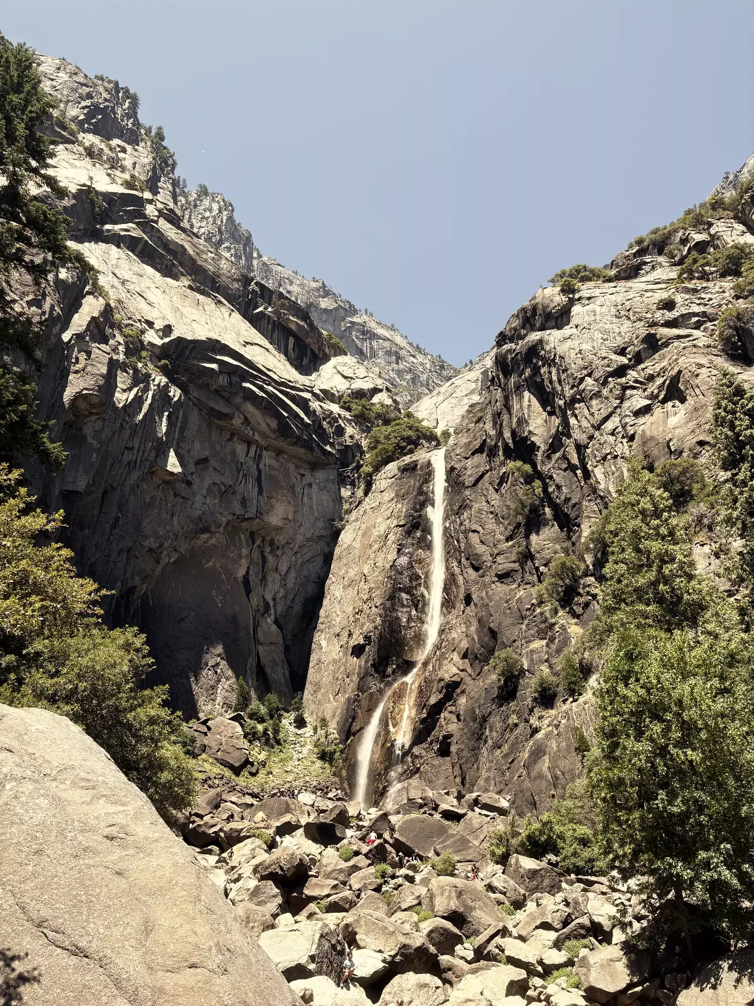 Smalle waterval die tussen hoge granieten rotswanden naar beneden stort in Yosemite National Park